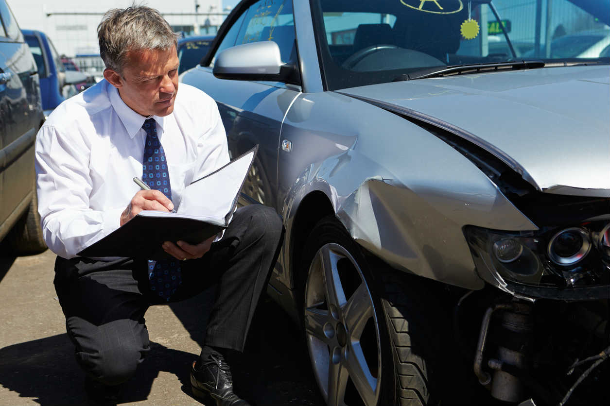 insurance adjuster examining car accident damage