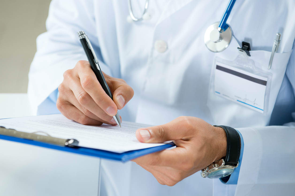 Male Doctor Writing On Medical Document