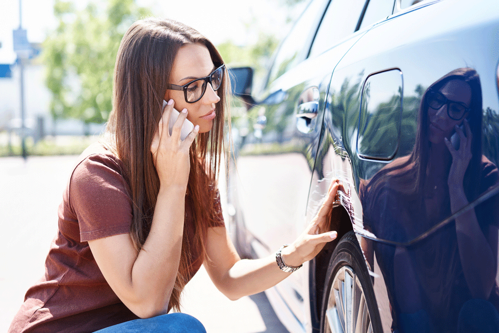 woman examining car damage