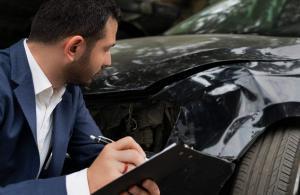 insurance adjuster examining car accident damage