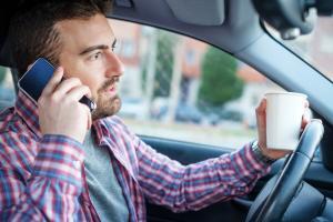 st. louis man using phone and drinking coffee while driving