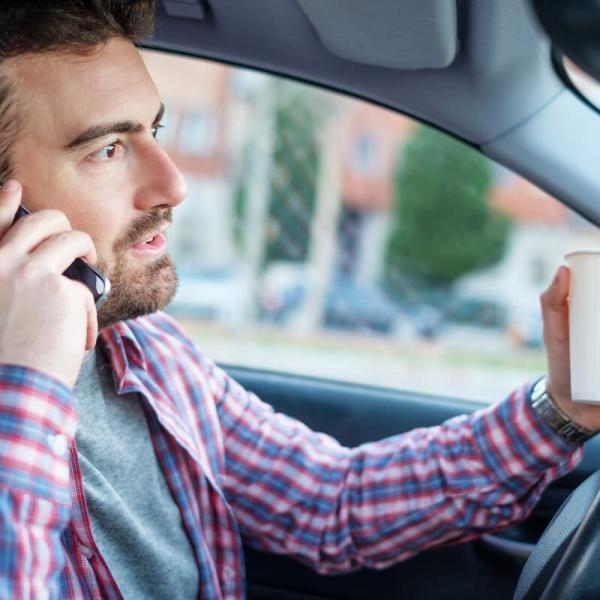 st. louis man using phone and drinking coffee while driving