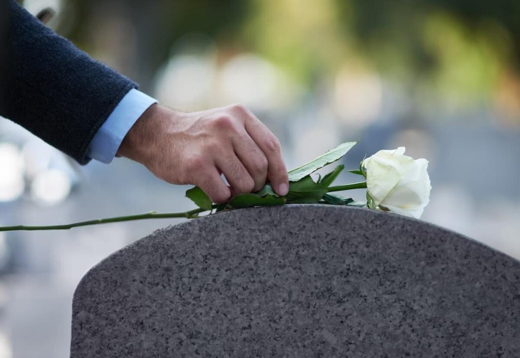 man placing a flower on gravestone