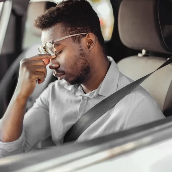 a drowsy driver rubs his eyes