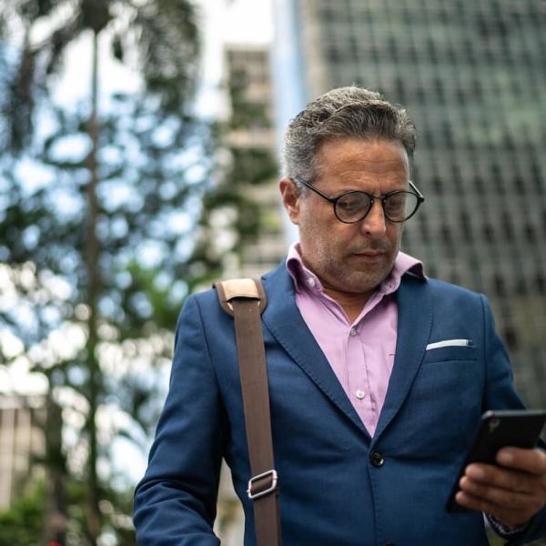 distracted man looking at his phone while crossing the road